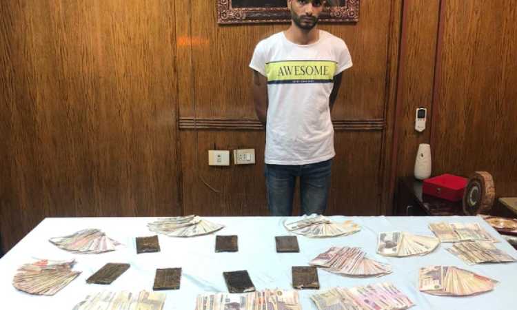 المتهم وأمامه المضبوطات